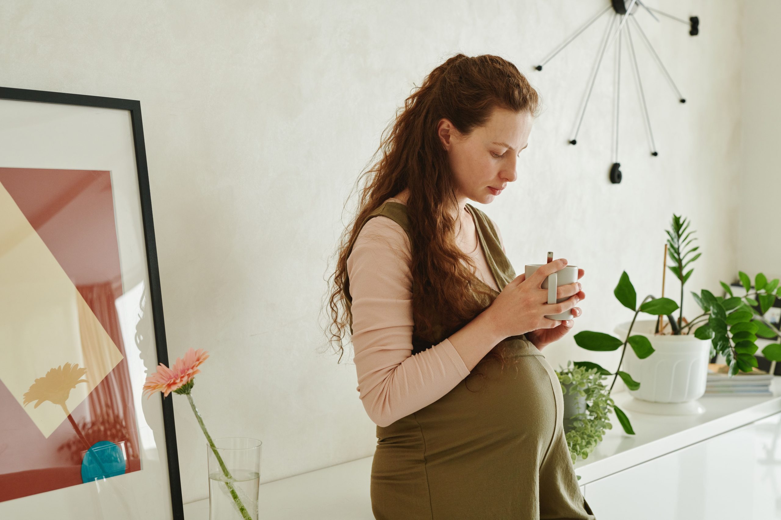 Femme enceinte avec tasse entourée de plantes