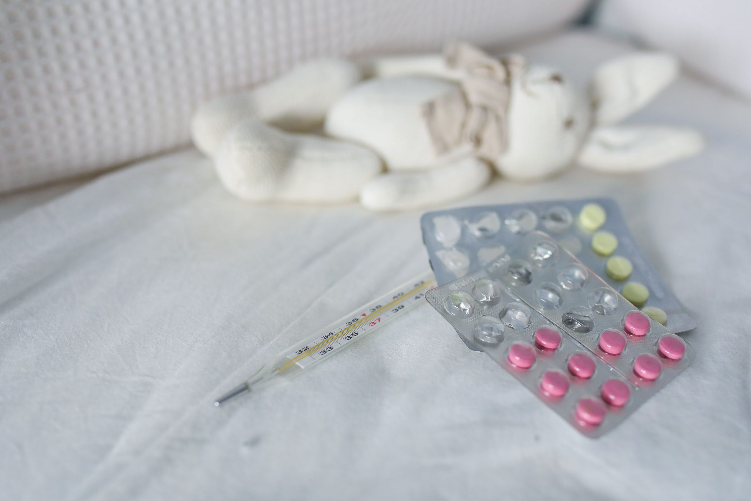 Médicaments et thermomètre près d'une peluche enfant