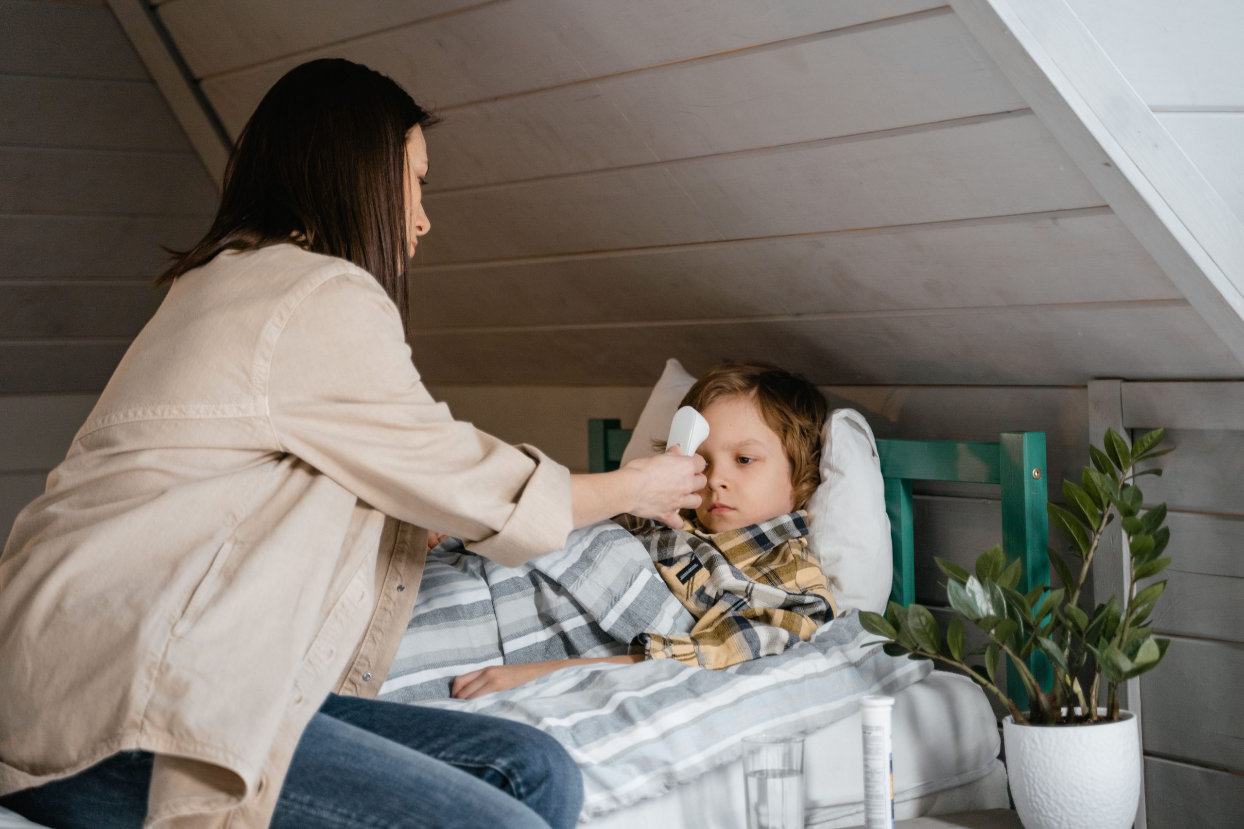 Mère prenant la température de son fils au lit