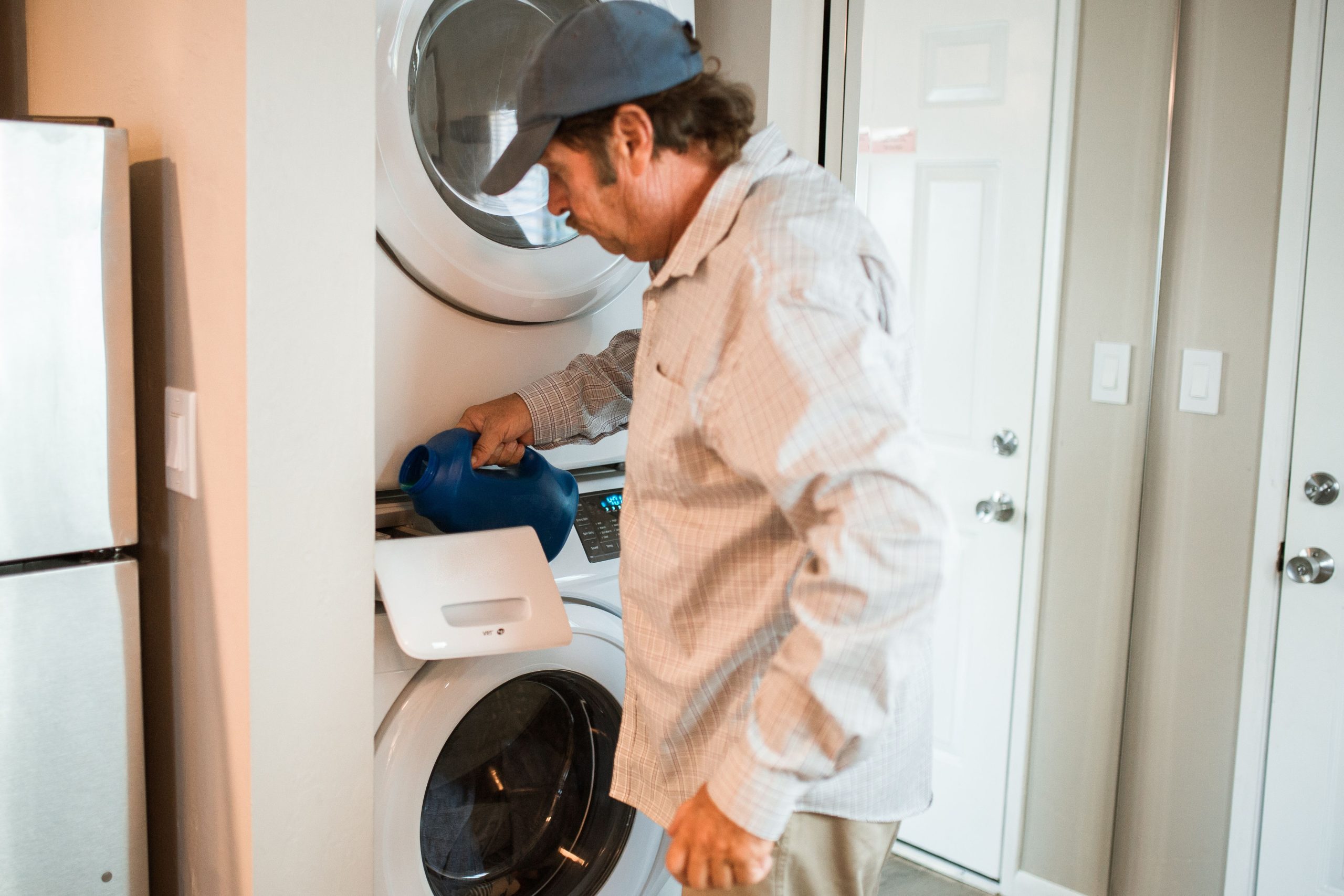 Homme versant détergent dans lave-linge moderne